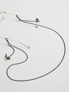 Detail of black eyewear chain featuring delicate butterfly pendants and rubber loop connectors
