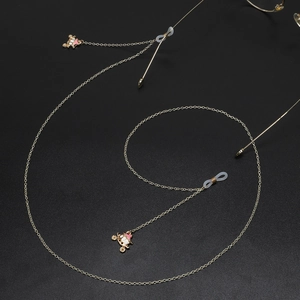 Chaîne de lunettes dorée avec pendentifs carrosse et boucles en silicone sur fond noir