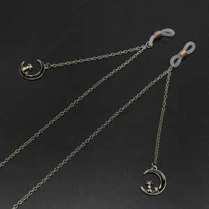 Golden eyewear chain with cat moon charms and anti-slip silicone loops on black surface