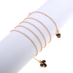 Golden eyewear chain with squirrel and pinecone charms on a white minimalist cylinder