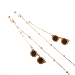 Golden eyewear chain with small beads and orange miniature sunglass charms on white background