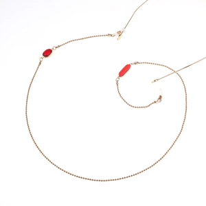 Détail de la chaîne à lunettes dorée avec perles de cristal rouges et boucles en silicone
