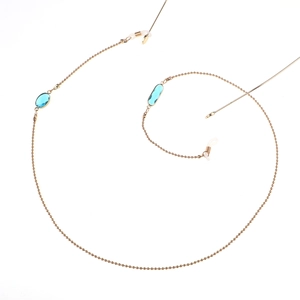 Détail de la chaîne de lunettes dorée avec breloques en cristal bleu et boucles