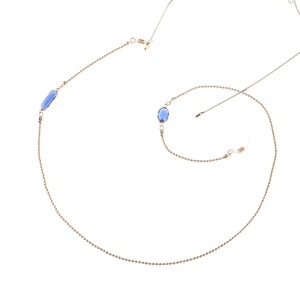 Détail du cordon de lunettes doré avec gemmes bleues foncées et boucles de réglage en silicone