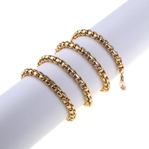 Polished gold box chain glasses strap with clear rubber loop ends on white prop