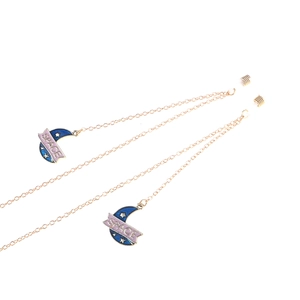 Chaîne de lunettes dorée avec pendentifs lune en émail bleu et étoiles sur fond blanc