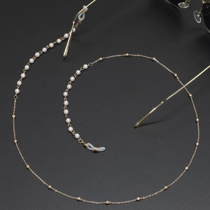 Chaîne à lunettes dorée élégante avec perles blanches sur fond sombre raffiné