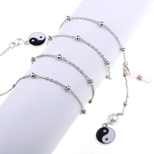 Silver metal eyewear chain with white pearls and Yin Yang Tai Chi charms on white stand