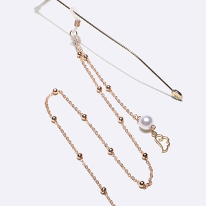 Détail de la chaîne de lunettes en or rose avec billes en métal et pendentif aile en perle