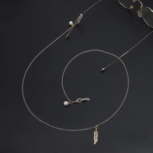 Golden metal glasses chain with elegant leaf pendant and pearls on black background