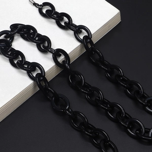 Minimalist black acrylic eyewear chain with oval links and shiny finish on books