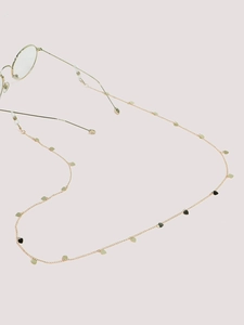 Détail de la chaîne de lunettes dorée avec pendentifs en cœur et embouts en silicone