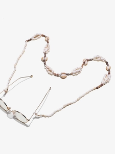 Close-up of a natural small seashell eyewear chain with gold metal finish connectors