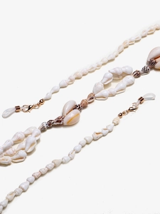 Detailed macro view of natural small sea shells and tiger striped snails on gold eyewear chain
