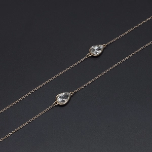 Goldene Metall-Brillenkette mit Wassertropfen-Anhängern auf schwarzem Hintergrund