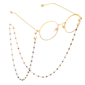 Fashionable handmade crystal beaded eyewear chain with gold round frame glasses on white base