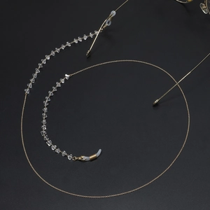 Golden chain eyeglass strap with transparent crystals and silicone loops on black background