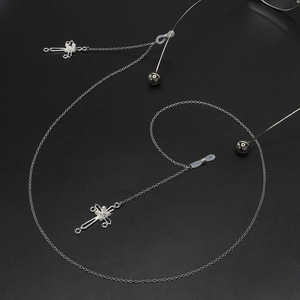 Catena per occhiali in metallo argento con ciondoli a croce e perle su sfondo scuro