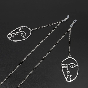 Silver metal eyewear chain featuring minimalist abstract face pendants on black background