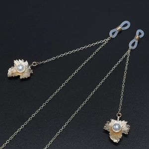 Golden eyewear chain with elegant maple leaf pendants and white pearls on black background