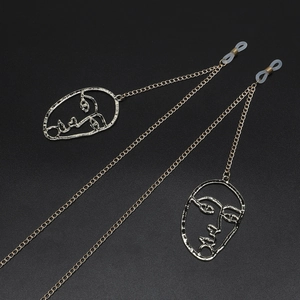Golden metal glasses chain featuring abstract face pendants and anti-slip silicone loops