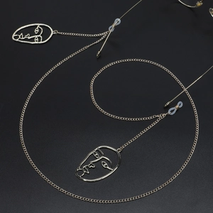Golden anti-slip eyewear chain with artistic abstract face charms on black background