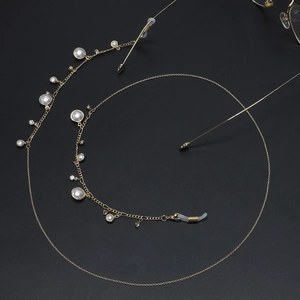 Elegante catenella per occhiali dorata con perle bianche e strass su fondo nero