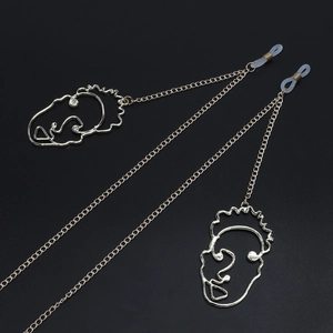 Détail de la chaîne de lunettes dorée avec pendentif artistique contour du visage