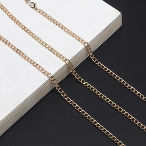 Polished gold metal eyeglass chain with lobster clasps on a modern black and white background