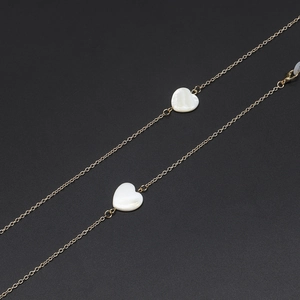 Handmade gold eyewear chain with white shell heart pendants on black background