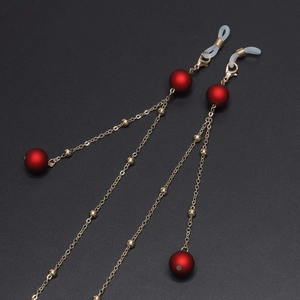 Golden eyewear chain with matte red beads and clear non-slip silicone loops on black base