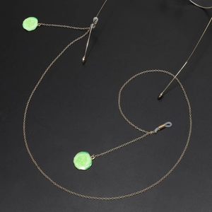 Golden metal eyewear chain featuring realistic green cucumber charms on black background