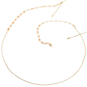 Chaîne de lunettes dorée avec cristaux transparents et perles d'ambre sur fond blanc