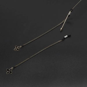 Dual black braided eyewear chains featuring gold four-leaf clover charms on matte background