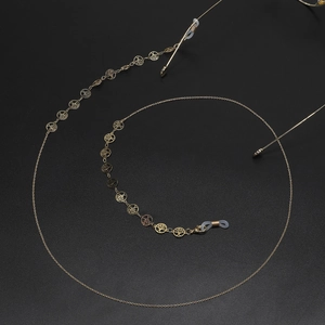 Handmade golden Tree of Life glasses chain with intricate metal cutouts on black background
