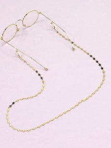 Détail des maillons en forme d'étoile sur chaîne de lunettes dorée sur fond violet doux