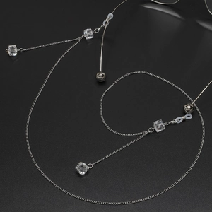 Chaîne de lunettes argentée avec cubes de cristal transparents et perles sur fond noir