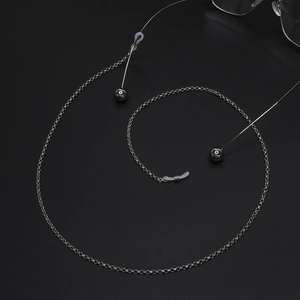 Silver metal eyeglasses chain with round links and spherical pendants on black background