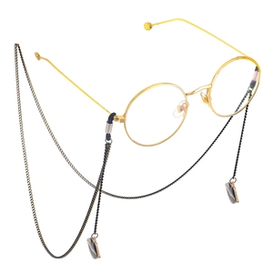 Fashionable gold round glasses with black lip pendant chain on white background