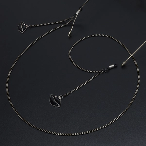 Chic eyewear chain with black enamel pendants and gold bead links on a dark background