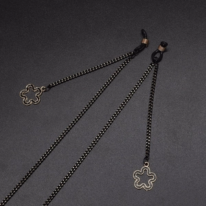 Fashion black woven glasses chain with gold hollow flower pendants on a dark background