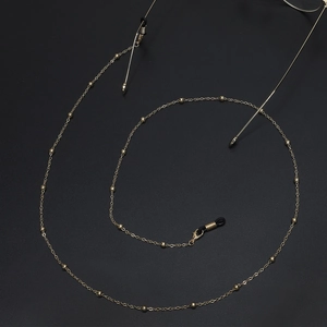 Elegant gold metal beaded eyeglass chain with black rubber loops on black background