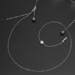 Chaîne à lunettes argentée avec pendentif éclair et perle blanche sur fond noir