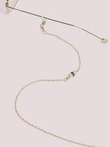 Detail of gold metal eyewear chain with white pearls and rhinestone black bead accents