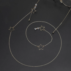 Goldene Brillenlkette aus Metall mit hohlen Sternanhängern auf schwarzem Hintergrund