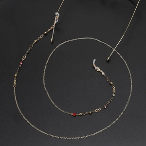 Chic gold eyewear chain with multi-colored crystals and infinity symbols on black background