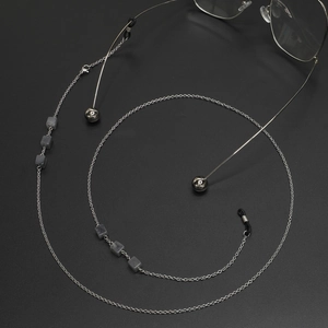 Silberne Brillenkette mit grauen Marmorperlen auf dunklem strukturiertem Grund