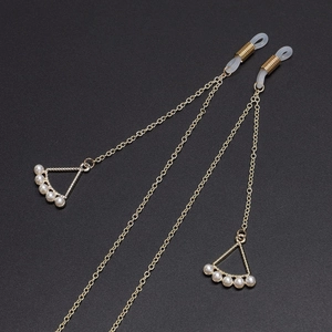 Golden metal eyewear chain with white pearls and hollow triangle pendant on dark background
