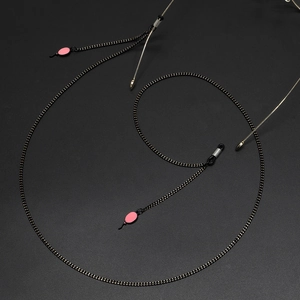 Chaîne à lunettes noire minimaliste avec pendentif rose vue sous un angle de 45 degrés