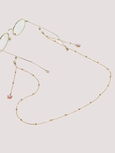Détail de la chaîne de lunettes dorée avec fleurs roses et perles dorées délicates